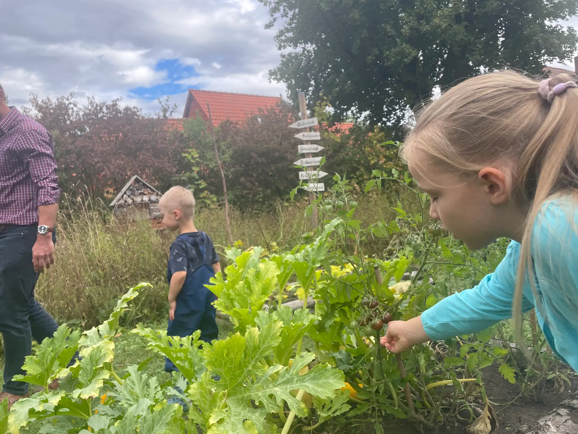 Kinder stehen vor bzw. auf einem Kinderacker und zeigen ihren Gästen, was beim Projekt „AckerRacker“ gewachsen ist.